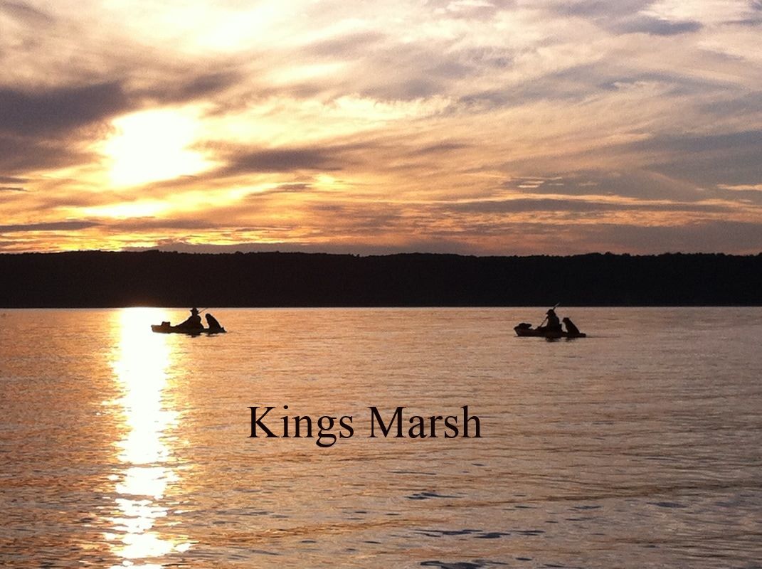 View of a lake with two boats with a sunset in the background