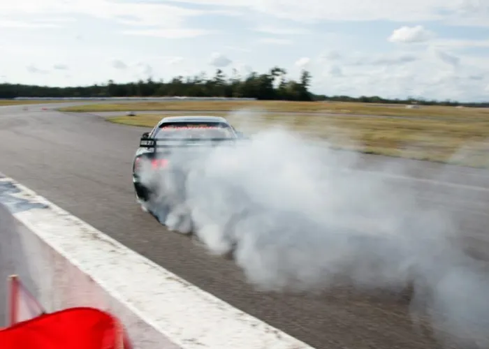 A car with smoke in behind on a race track