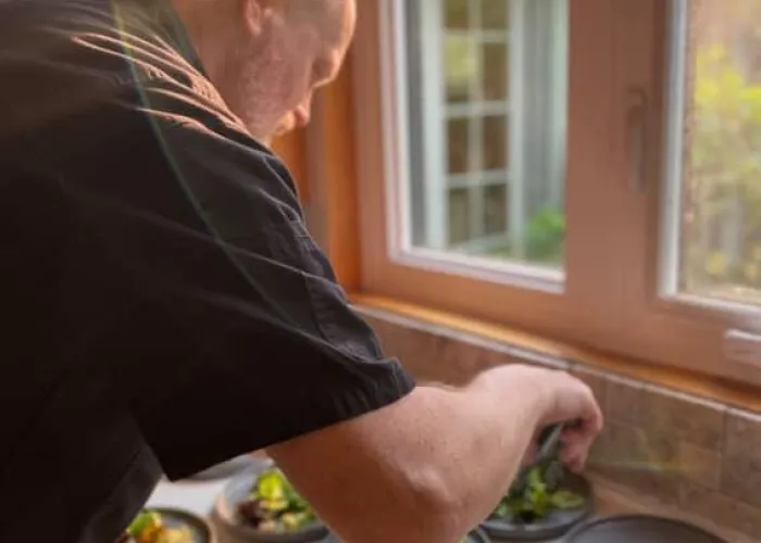 photo of chef adding food to multiple plates