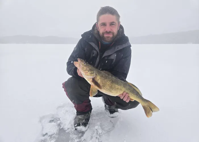 man holding a fish on an ice covered lake