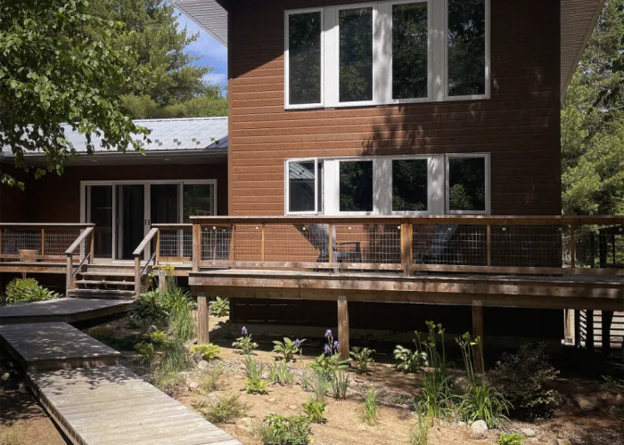 Front exterior of Cedarhaus B&B. A brown building with a large deck and white windows.