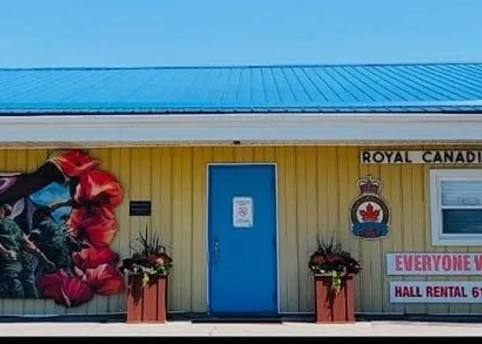 Photo of building with blue roof, mural with soldiers, canadian flag and poppies on the side, blue door, and legion sign