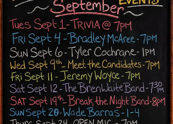 AI chalkboard with venue logo burned into wood at top, list of September events written in colourful chalk