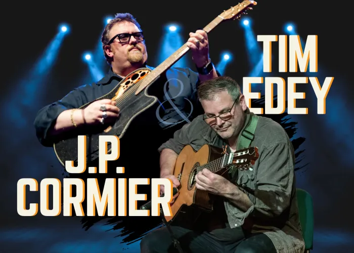 JP Cormier and Tim Edey together playing acoustic guitars, spot lights in background